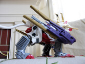 Side view of Kingliger wearing the Wind Dancer custom part, which is large purple and gold boosters attached to its front legs